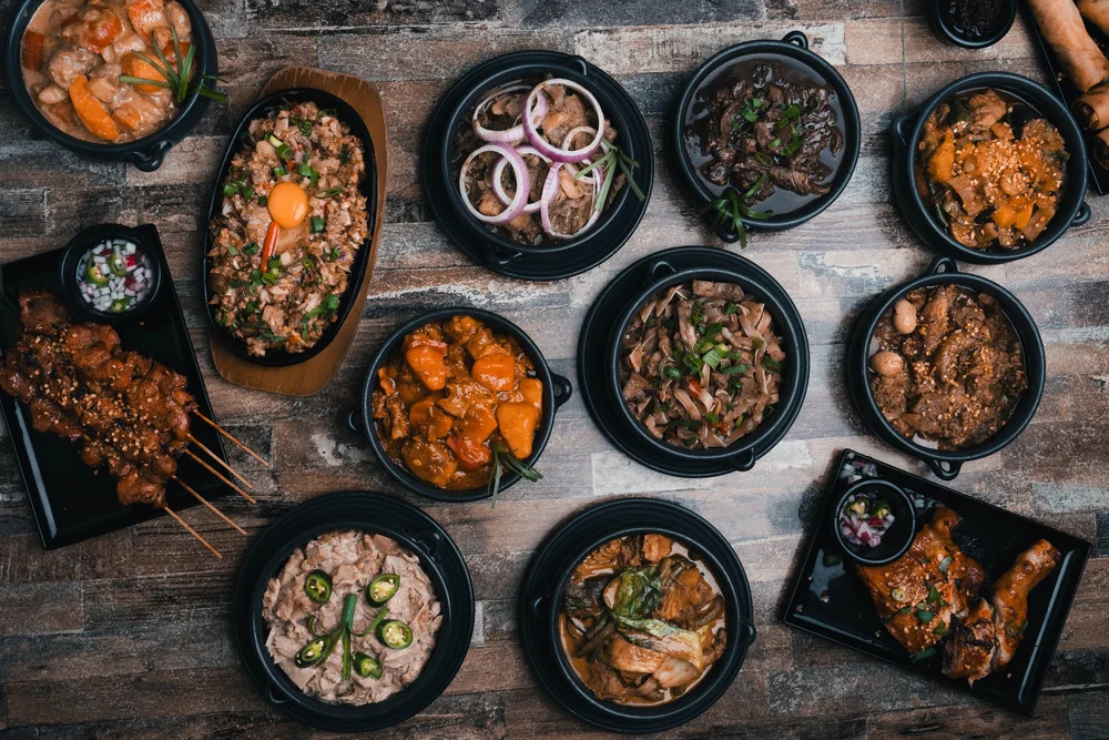 Overhead spread of Filipino dishes on timber table