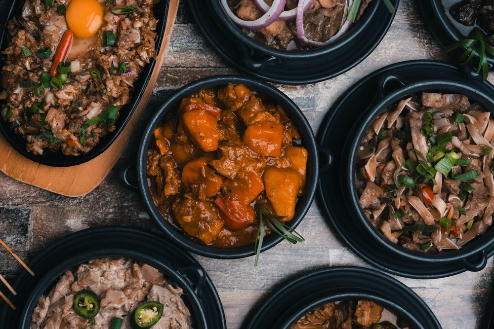 Filipino feast — sizzling sisig and kare-kare in claypots