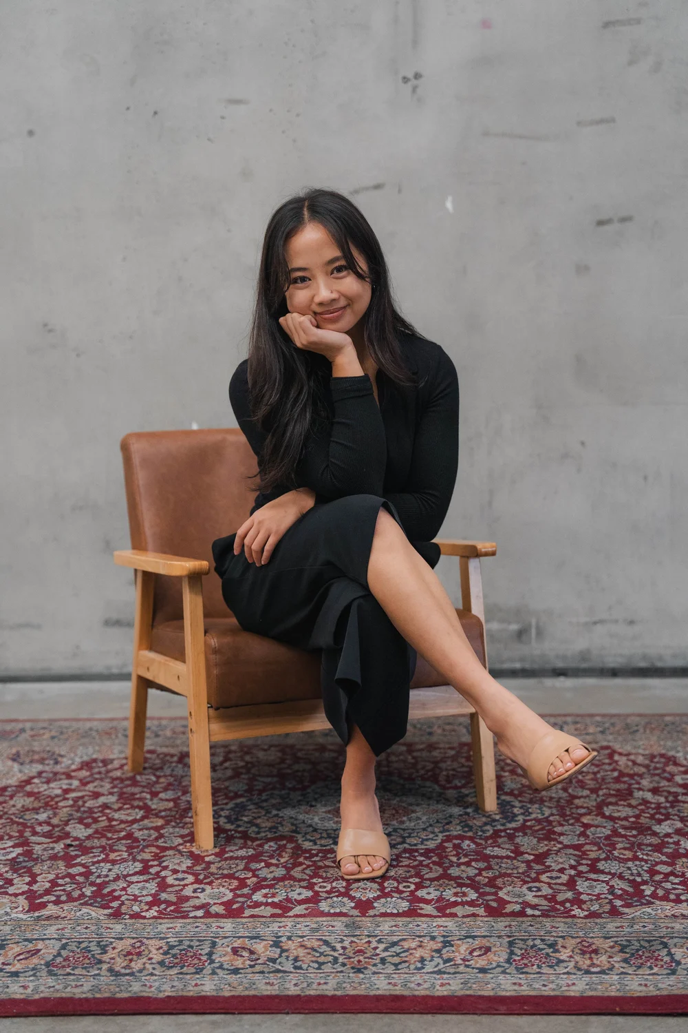 Seated editorial portrait on leather chair with Persian rug