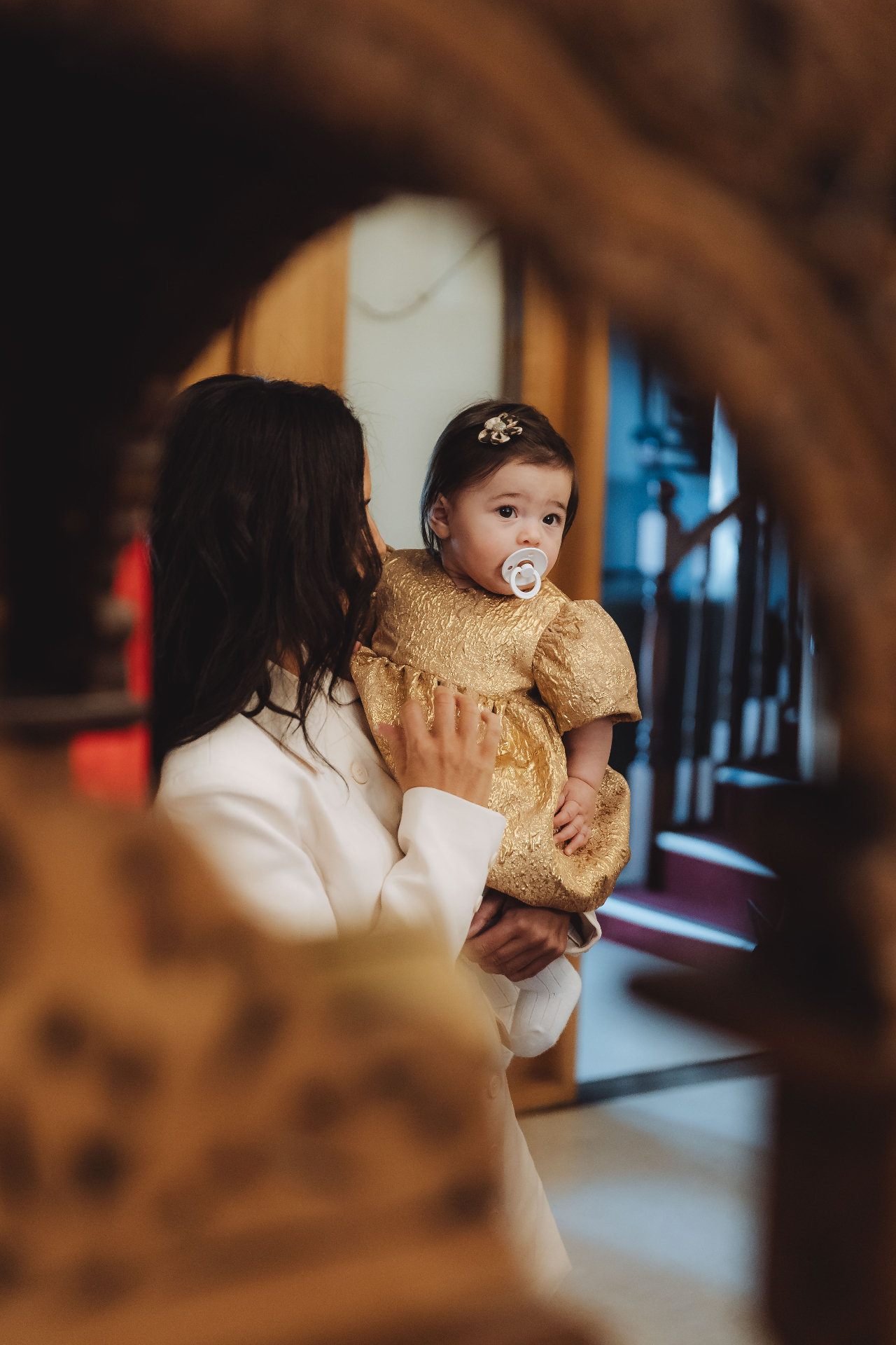 Baby in gold dress framed through arch