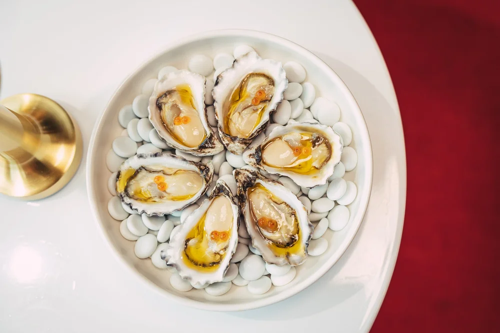 Fresh oysters with caviar on white platter
